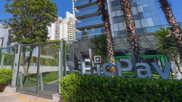 Fachada de prédio com o letreiro do PicPay cercada de árvores, na matéria sobre a conta de publicidade do banco digital